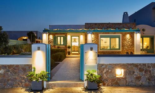 a house with a stone wall and blue columns at Almyriki Beach Villa in Monolithos