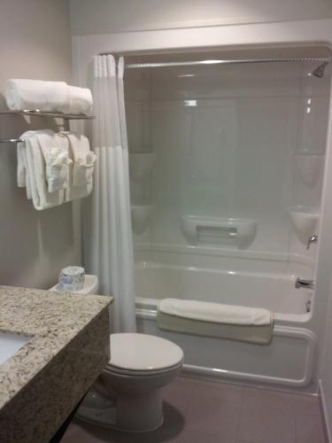 a bathroom with a shower and a toilet and a tub at Midland Inn & Suites in Midland