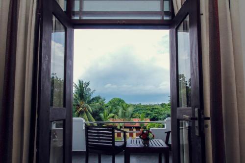 an open door to a balcony with a view of trees at Rockery Villa Ayurveda in Bentota
