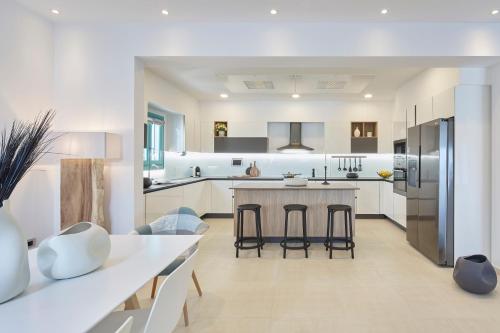 a kitchen with white cabinets and a kitchen island with bar stools at Almyriki Beach Villa in Monolithos