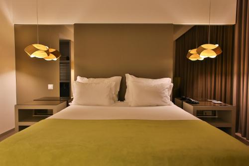 a bedroom with a large bed with two lamps at Delfim Douro Hotel in Lamego