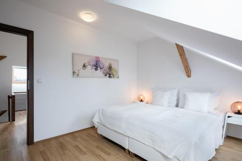 a white bedroom with a white bed and a mirror at Pytloun Apartments Liberec in Liberec