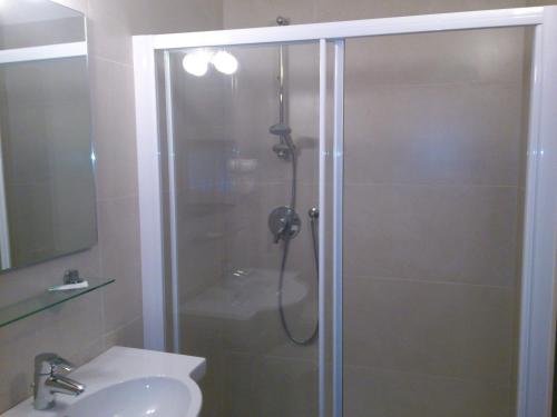 une douche avec une porte en verre à côté d'un lavabo dans l'établissement Hotel Toresela Bike am Gardasee, à Nago-Torbole