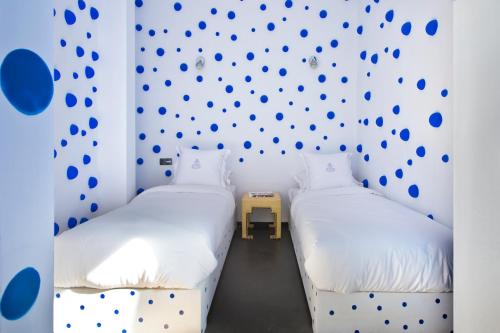 two beds in a room with a wall with blue dots at Riad Goloboy in Marrakech