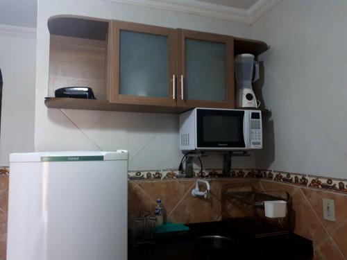 uma cozinha com um frigorífico e um micro-ondas em Casa da Josi - Pajuçara em Maceió