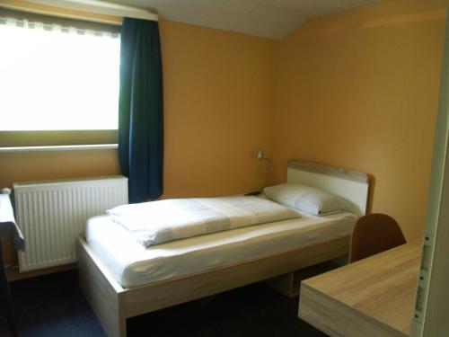 a bedroom with a bed and a window and a table at Waldpension zum Felsenkeller in Lichtenfels-Sachsenberg