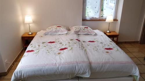 a bed with a white comforter with flowers on it at Maison des écluses Strasbourg F3 90m2 Jacuzzi Climatisation in Strasbourg
