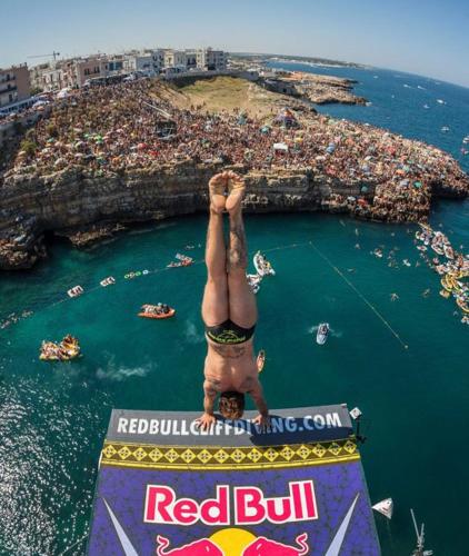 a man doing a handstand on a sign in the water at Casa Mirò in Polignano a Mare