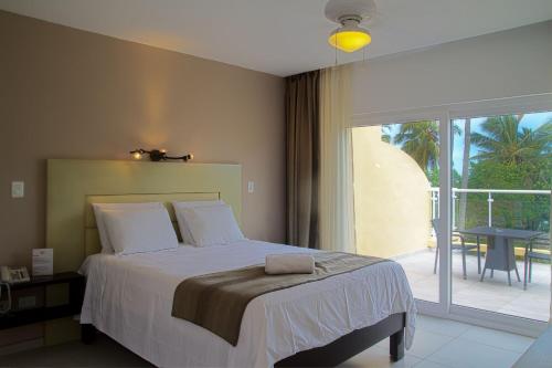 a bedroom with a bed and a balcony with a table at Hotel Villa Taina in Cabarete