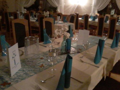 a table with wine glasses and blue napkins on it at Waldpension zum Felsenkeller in Lichtenfels-Sachsenberg