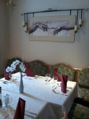 a dining table with a white table cloth and red chairs at Waldpension zum Felsenkeller in Lichtenfels-Sachsenberg