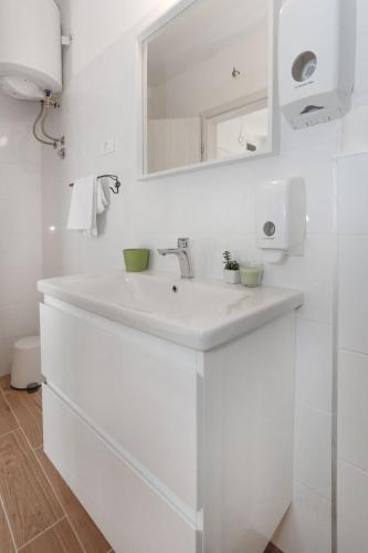 a white bathroom with a sink and a mirror at Apartments and Rooms Stone House in Split