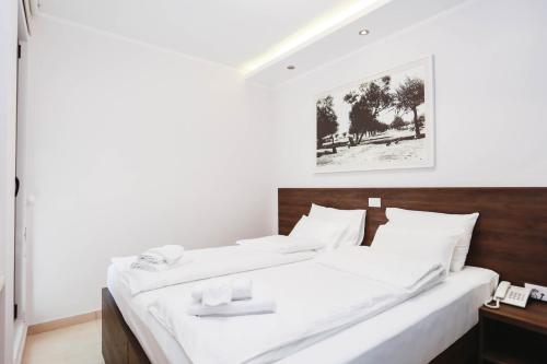 a bedroom with a large bed with white sheets at Arka Rooms&Apartments in Budva