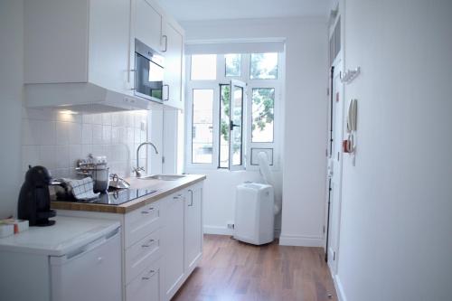 eine weiße Küche mit einer Spüle und einem Kühlschrank in der Unterkunft Ribeira Funchal Center in Funchal