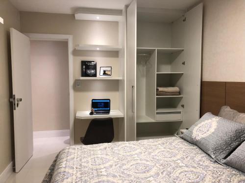 Un dormitorio con una cama y un escritorio con una computadora portátil. en Ondina Apart Hotel - Apto. 537, en Salvador