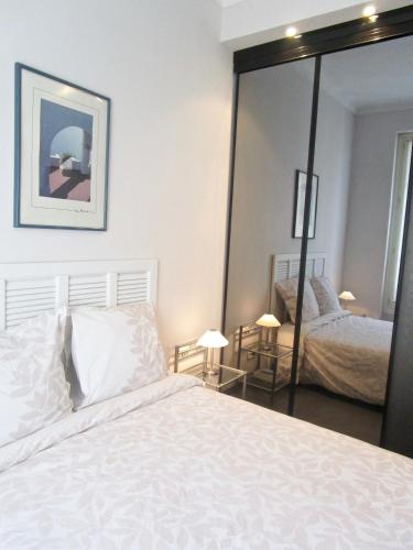 une chambre avec un lit blanc et un grand miroir dans l'établissement Appartement, à Nice