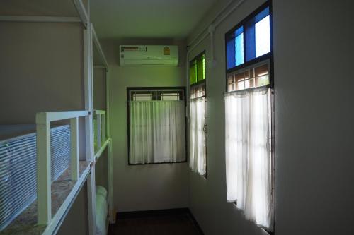 Habitación pequeña con 2 ventanas y escalera. en Insight Hostel, en Chiang Mai