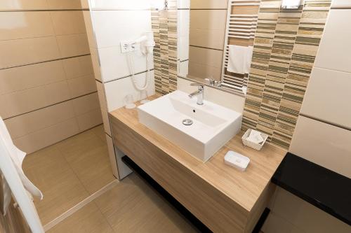 a bathroom with a sink and a mirror at Hotel Zena Beauty & Shopping Center in Hévíz
