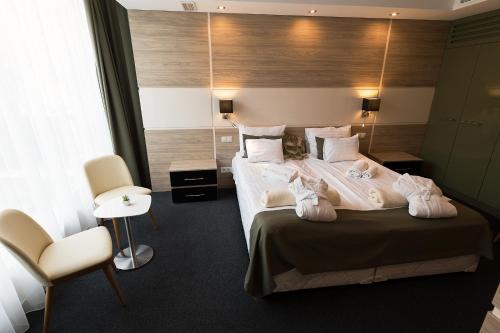 a hotel room with a bed and a chair at Hotel Zena Beauty & Shopping Center in Hévíz