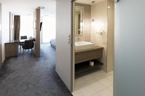 a bathroom with a sink and a mirror and a desk at Hotel Zena Beauty & Shopping Center in Hévíz
