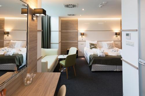 a hotel room with two beds and a desk at Hotel Zena Beauty & Shopping Center in Hévíz