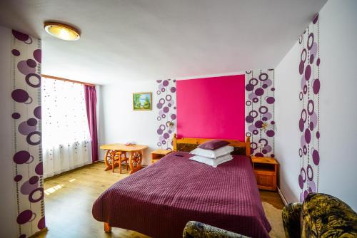 a bedroom with a purple bed with a pink wall at Pensiunea Iozefina in Moieciu de Jos
