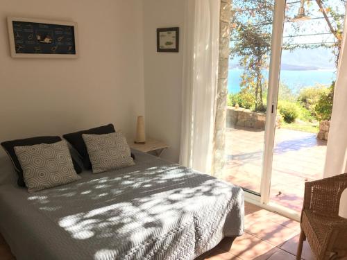 a bedroom with a bed and a sliding glass door at Villas Valinco Capicciolo vue-proche mer-piscines in Olmeto