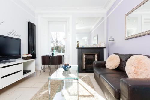 a living room with a black leather couch and a tv at Edinburgh Near Centre Luxury Apartment in Edinburgh