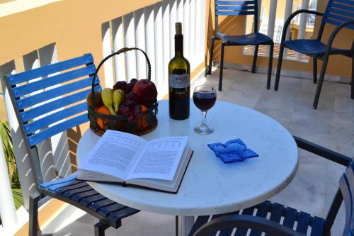 a table with a book and a bottle of wine and a basket of fruit at Futura Hotel in Maleme