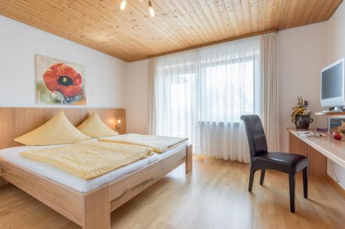 a bedroom with a bed and a desk and a chair at Pension Zum Ebenstein am Donausteig in Untergriesbach