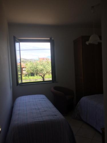 una camera con letto e finestra con albero di La Stradina a Castellammare di Velia