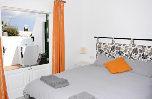 a bedroom with a bed with an orange pillow at Casa Melera in Costa Teguise