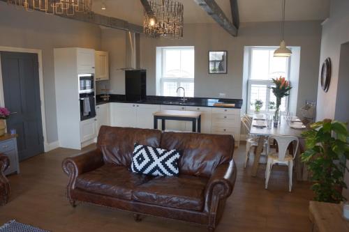 a leather couch in a living room with a kitchen at Hide Hill, Berwick Upon Tweed in Berwick-Upon-Tweed