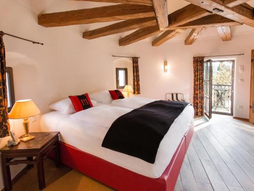 - une chambre avec un grand lit dans une pièce dotée de plafonds en bois dans l'établissement DORMERO Schlosshotel Reichenschwand, à Reichenschwand