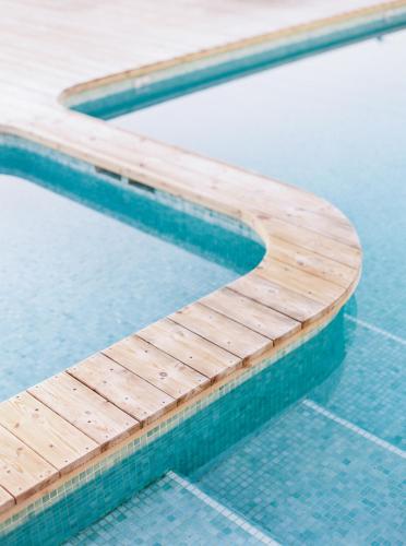 a wooden bench sitting in a swimming pool at Conversas de Alpendre in Vila Nova de Cacela
