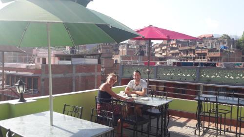 two women sitting at a table on a balcony with an umbrella at Hotel Bhaktapur Inn in Bhaktapur