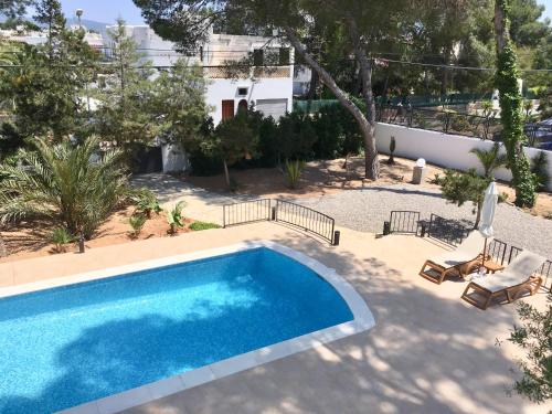 a swimming pool in a yard with two lounge chairs at Chalet Torralba - Villa at Hotel Osiris in San Antonio