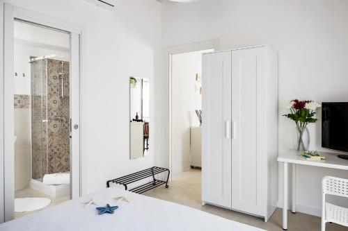 una camera da letto bianca con armadio bianco e TV di Casa Vacanze "Oceano mare" a Pozzallo