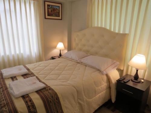 a bedroom with a large white bed with two lamps at Apartamento Familiar QUEWE in Cusco