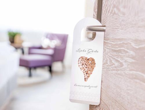 a door opener with a heart shaped tag on a door at Fichtenwald-Ihr Boutique I Glück`s Hotel in Bad Füssing