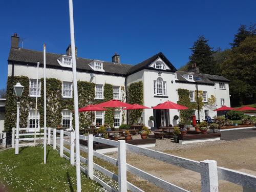 a white building with red umbrellas in front of it at Llwyngwair Manor, Newport, PEMBROKESHIRE in Newport