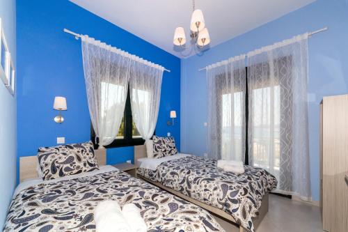 a bedroom with two beds and blue walls at Agapitos Apartments in Nikiti