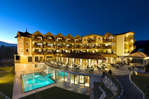 a large hotel with a swimming pool at night at Hotel Chalet Tianes - Alpine Relax in Castelrotto