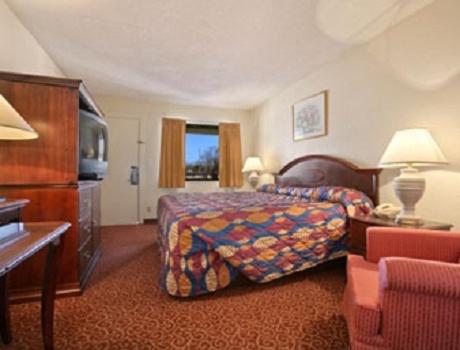 a hotel room with a bed and a television at Park Hill Inn and Suites in Oklahoma City