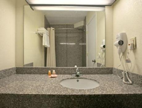 a bathroom with a sink and a large mirror at Park Hill Inn and Suites in Oklahoma City