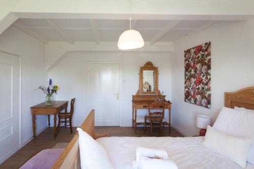a bedroom with a bed and a table and a desk at De Oude Pastorie Macharen in Macharen