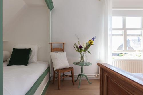 a bedroom with a bed and a table with a vase of flowers at De Oude Pastorie Macharen in Macharen