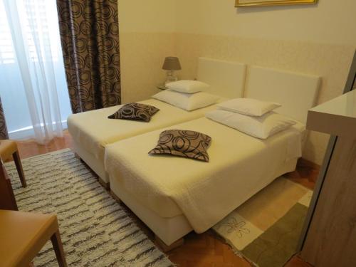 a bedroom with two beds with white sheets and pillows at Guesthouse Vrlic in Split