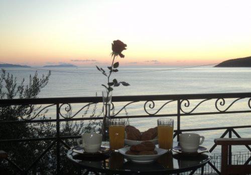 a table with food and drinks on a balcony overlooking the ocean at Polichni in Leonidion