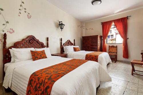 a hotel room with two beds and a window at Hotel Agua Escondida in Taxco de Alarcón